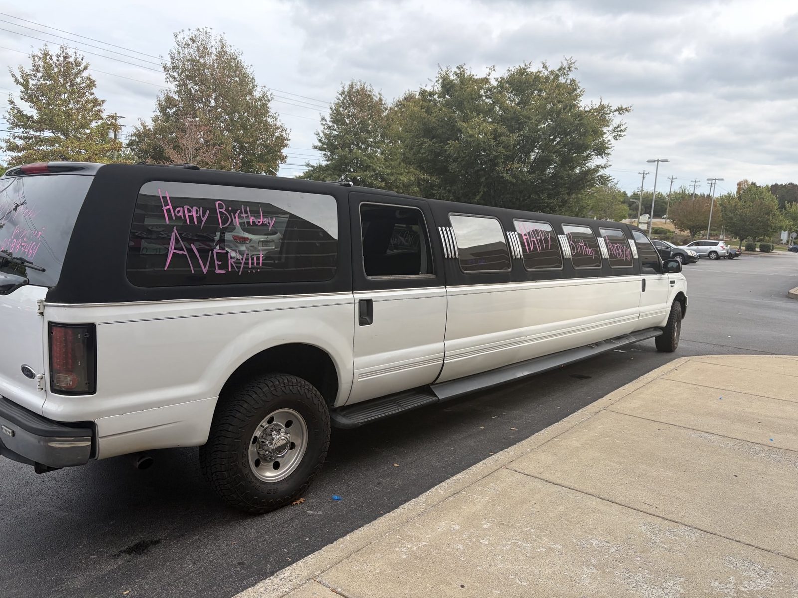 White Excursion stretch party limo with Happy Birthday written in pink on the windows in Nashville
