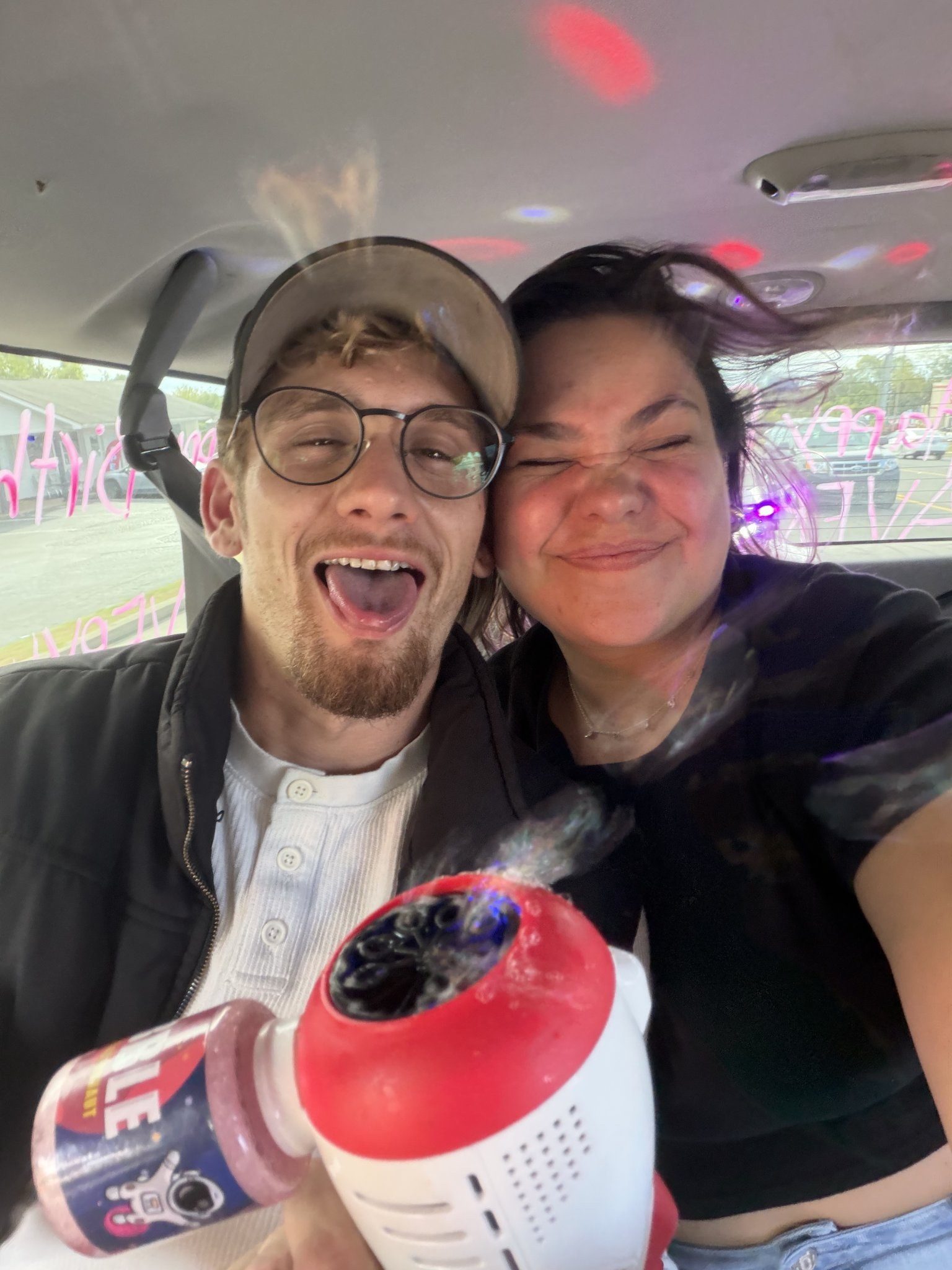 Couple playing with the bubble machine inside the karaoke limo in Nashville under colorful party lights